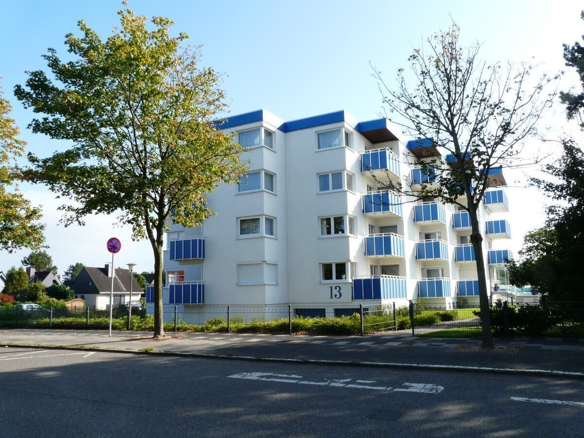 A multi-story residential building with balconies, a no parking sign, and a clear sky.