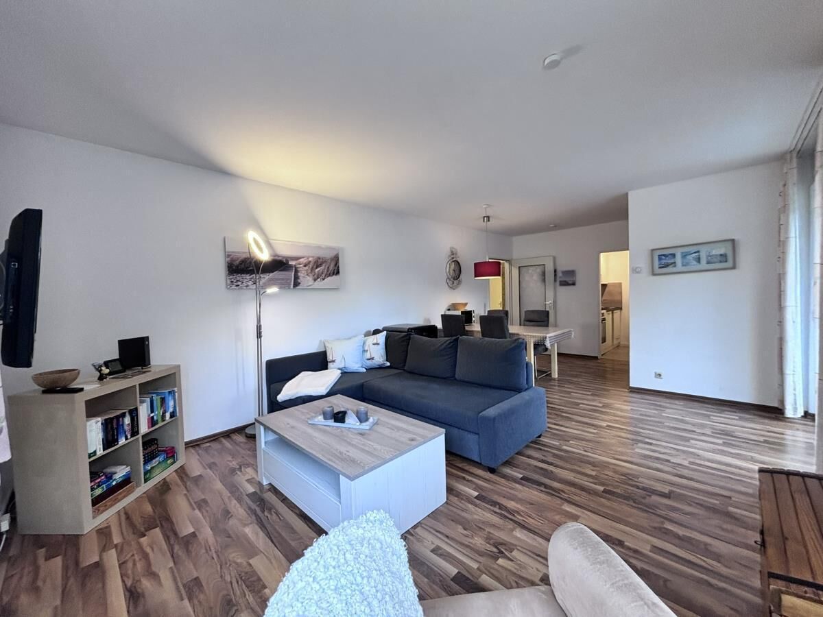 Una sala de estar moderna con un sofá azul, una mesa de centro blanca y una estantería.