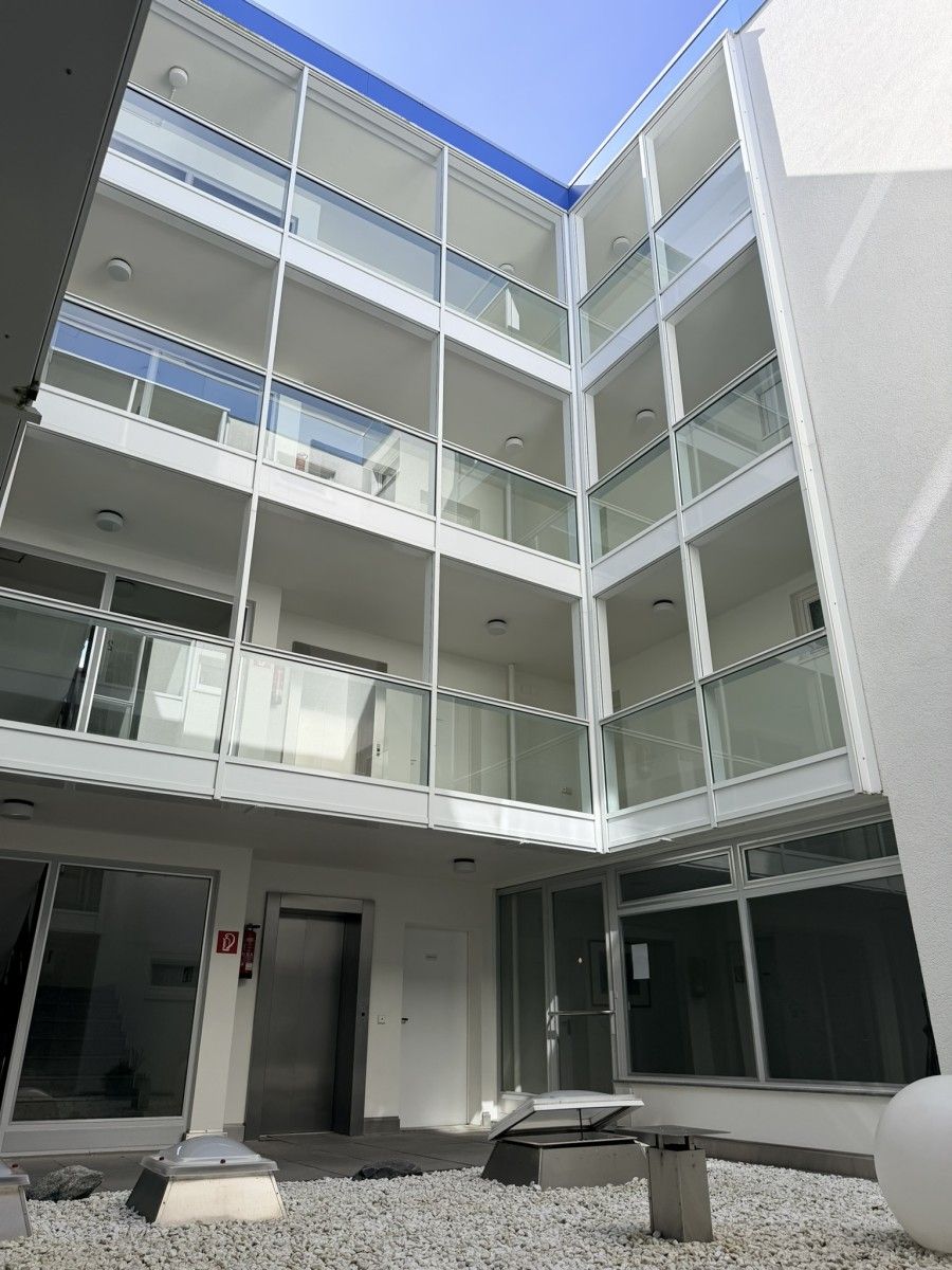 En bygning med flere etager, en glasfacade, et fladt tag og en dør med en brandslukker.