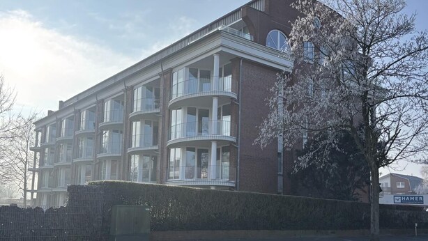 Ein mehrstöckiges Gebäude mit Ziegelverkleidung, großen Fenstern und Balkonen.