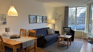 Ein modernes Wohnzimmer mit Essbereich, ausgestattet mit einer Couch, einem Couchtisch und einem Esstisch mit Stühlen.