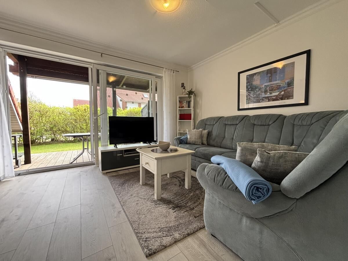 A living room with a grey sofa, a small white table, and a TV.