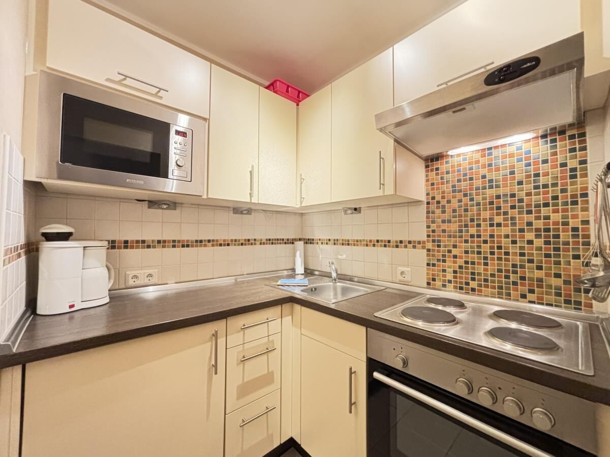 A compact kitchen with a microwave, stove, and coffee maker.