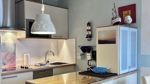 Una cocina moderna con una isla central, estufa integrada y una lámpara colgante.