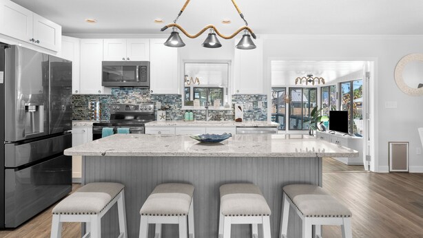 Una cucina moderna con una grande isola, elettrodomestici in acciaio inossidabile e un originale lampadario.