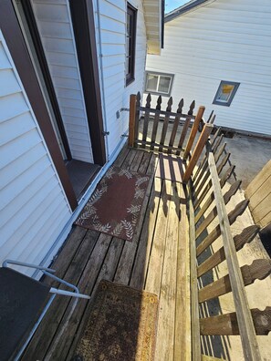 A wooden deck with a metal chair, a wooden fence, and a door leading to a house. - Travelers Dream 1-bedroom apartment in Seattle perfect location to see the Games (Seattle)