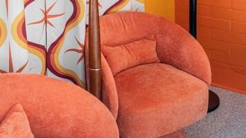 Una habitación con dos sillones tapizados en naranja y una cortina estampada.