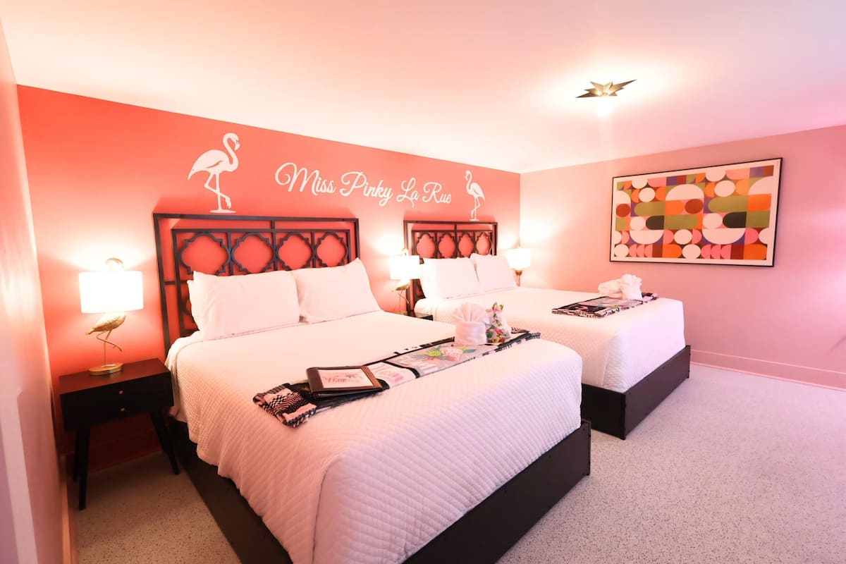 Een hotelkamer met twee bedden, een muurschildering en een decoratief bord.