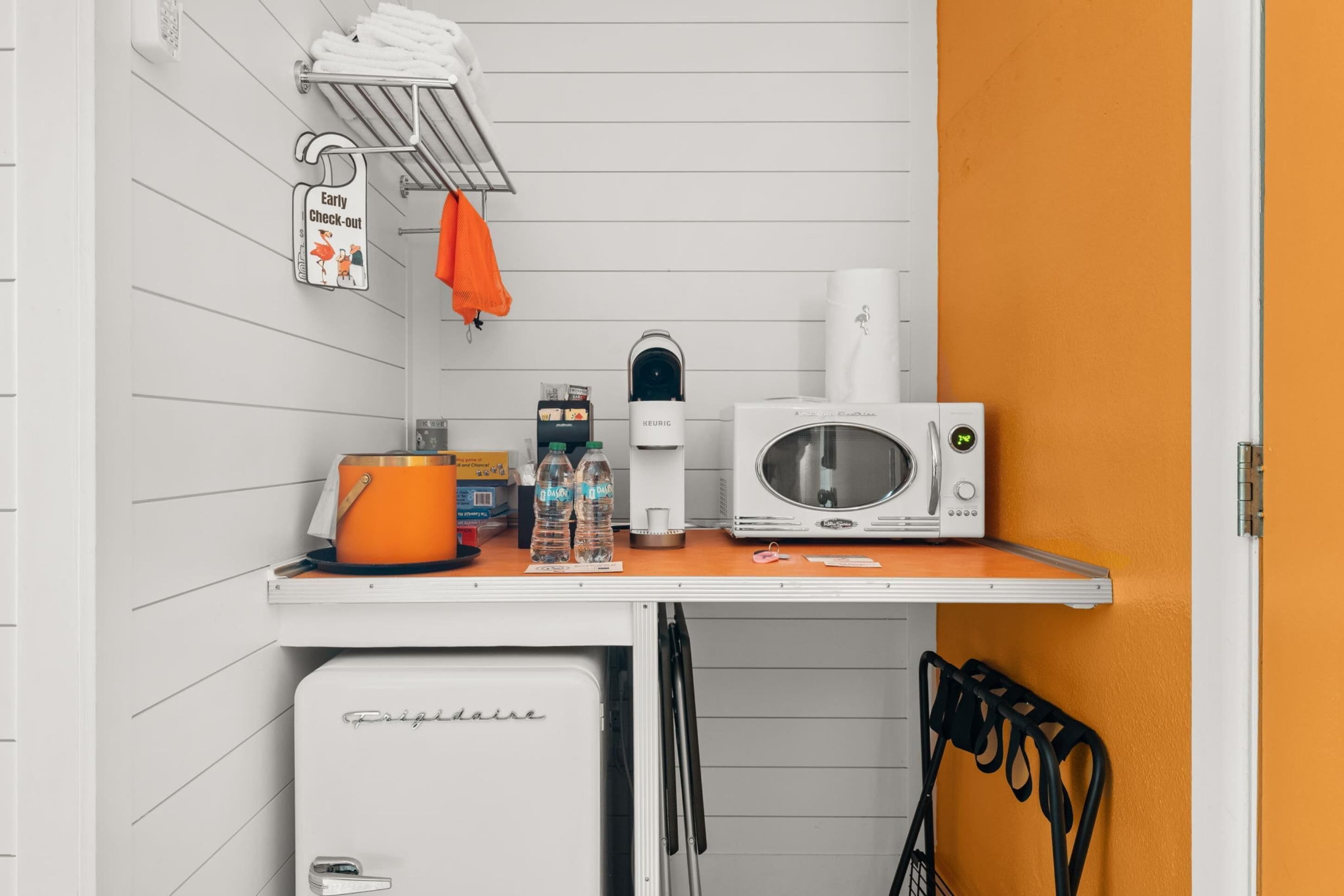A kitchenette with a white refrigerator, a microwave, a kettle, and a coffee maker.