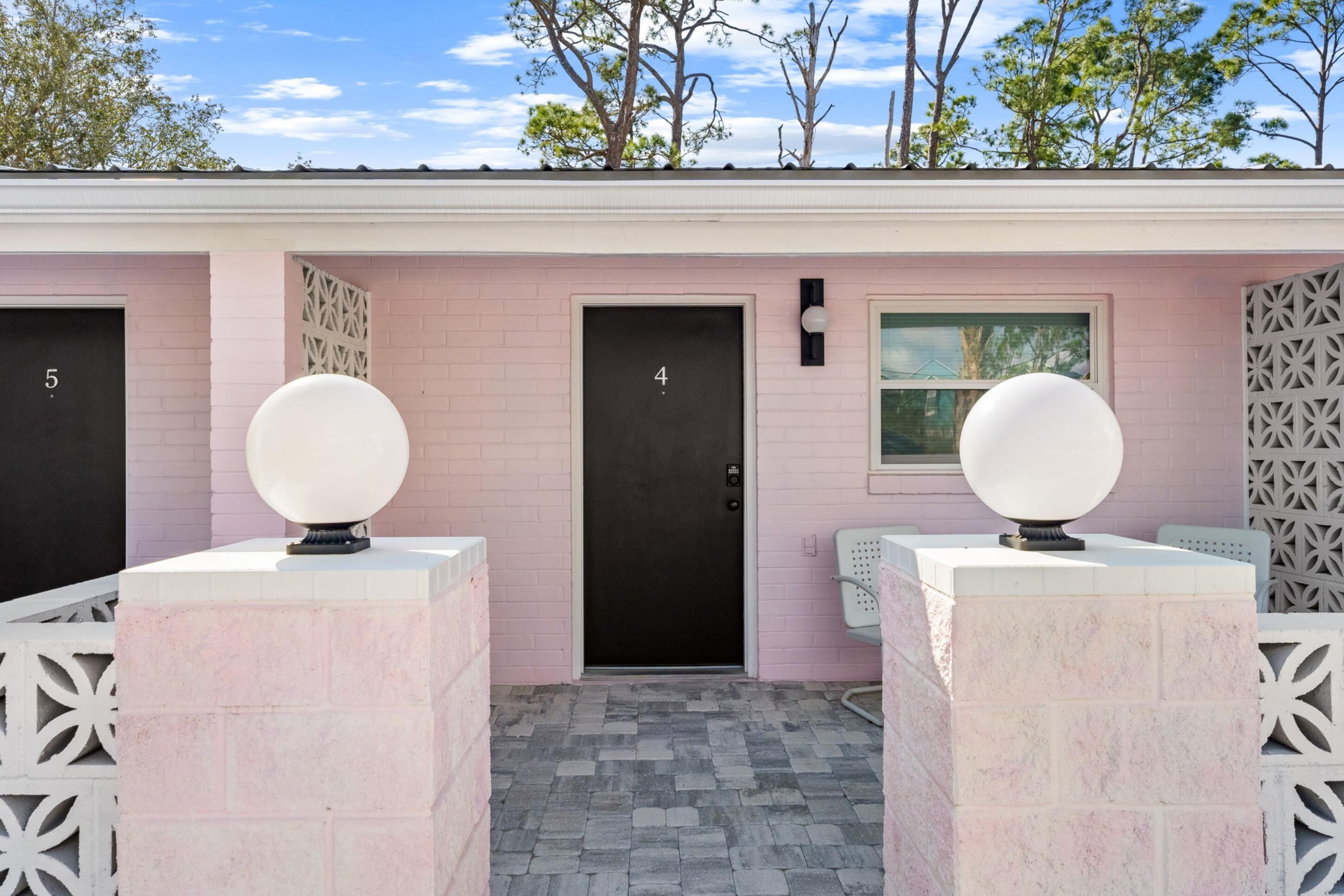 A row of pink brick buildings with numbered doors, each with a white spherical object on top.