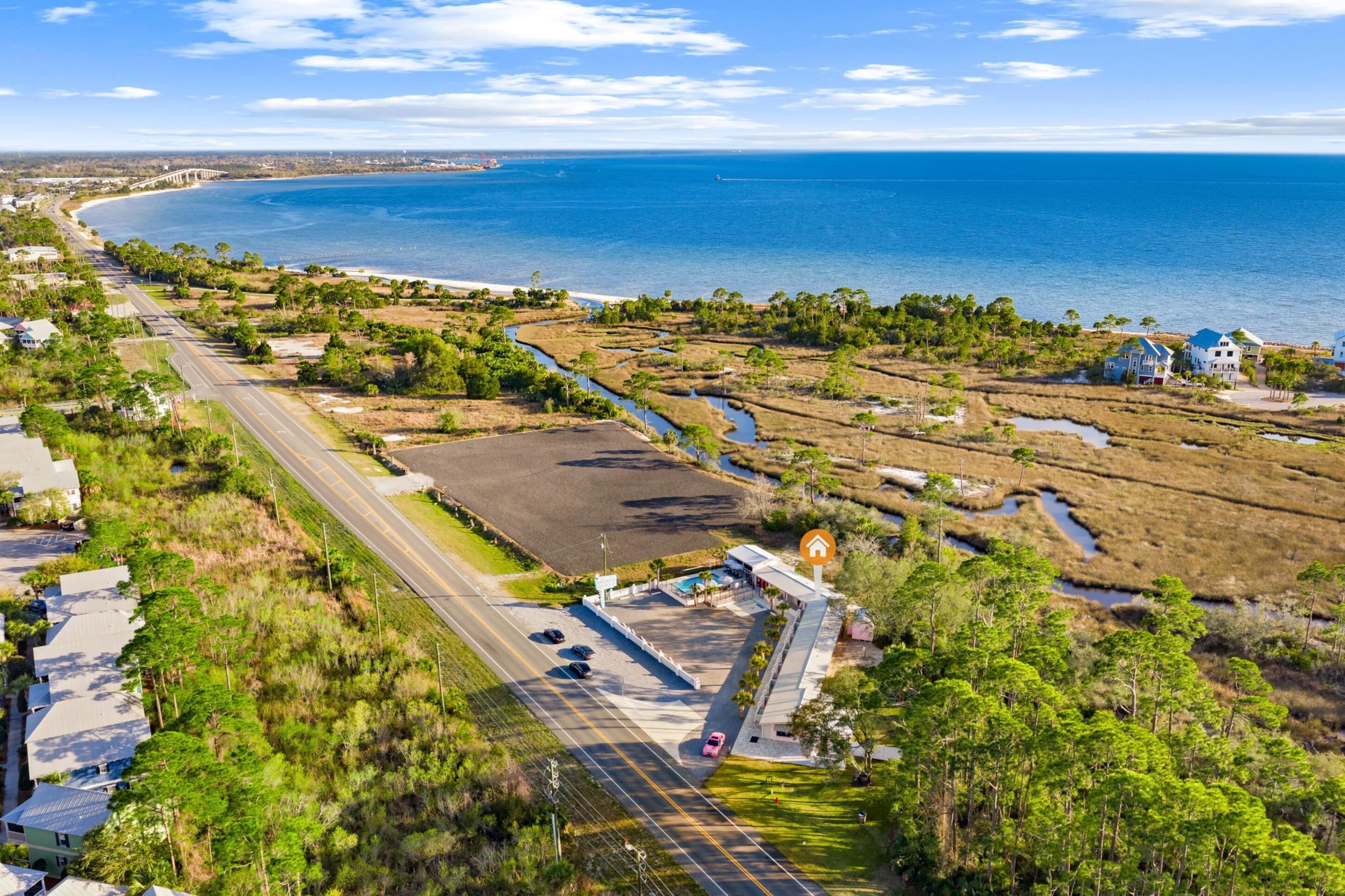 Vue aérienne d’une zone côtière avec une route, des bâtiments et une plage.