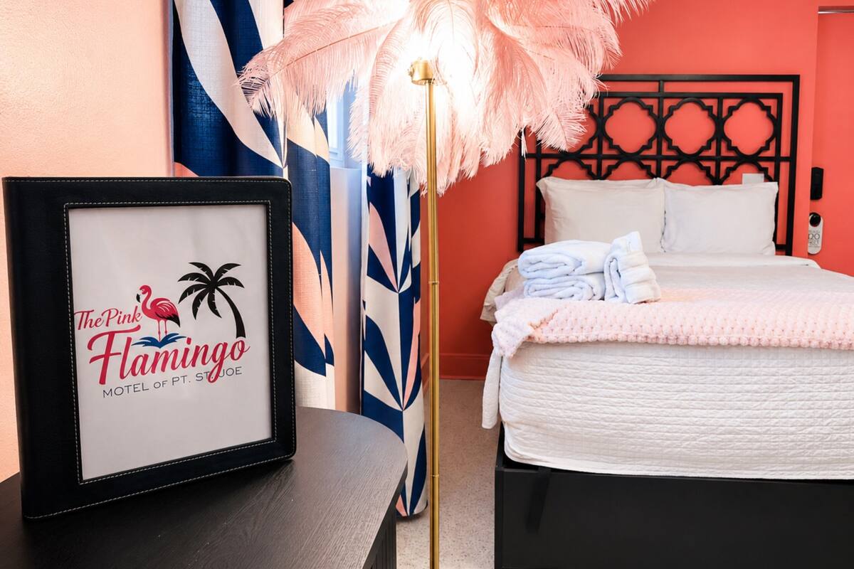 Een hotelkamer met een bed, een lijst, een decoratieve lamp en een muur met een geometrisch patroon.