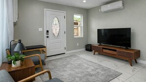 Ein Wohnzimmer mit Fernseher, Sofa und einer Tür mit dekorativer Glasscheibe.