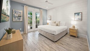 Une chambre à coucher avec un lit, des tables de chevet, un bureau et une plante en pot.