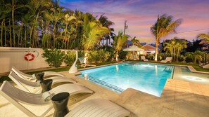 Une piscine avec des chaises longues, une bouée de sauvetage et des palmiers.