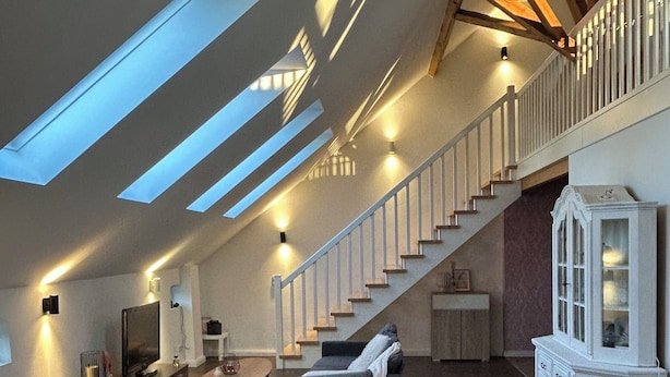 Ein geräumiges Loft mit hohen Decken, Dachfenstern, einer Treppe und einer gemütlichen Sitzecke.