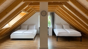 Ein Zimmer mit zwei Betten, Holzbalken, einer Uhr und einem Fenster.