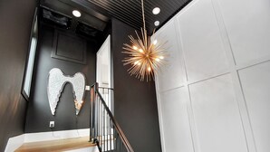 Een trap met een zwarte balustrade, een wandlamp en een decoratief wandobject.