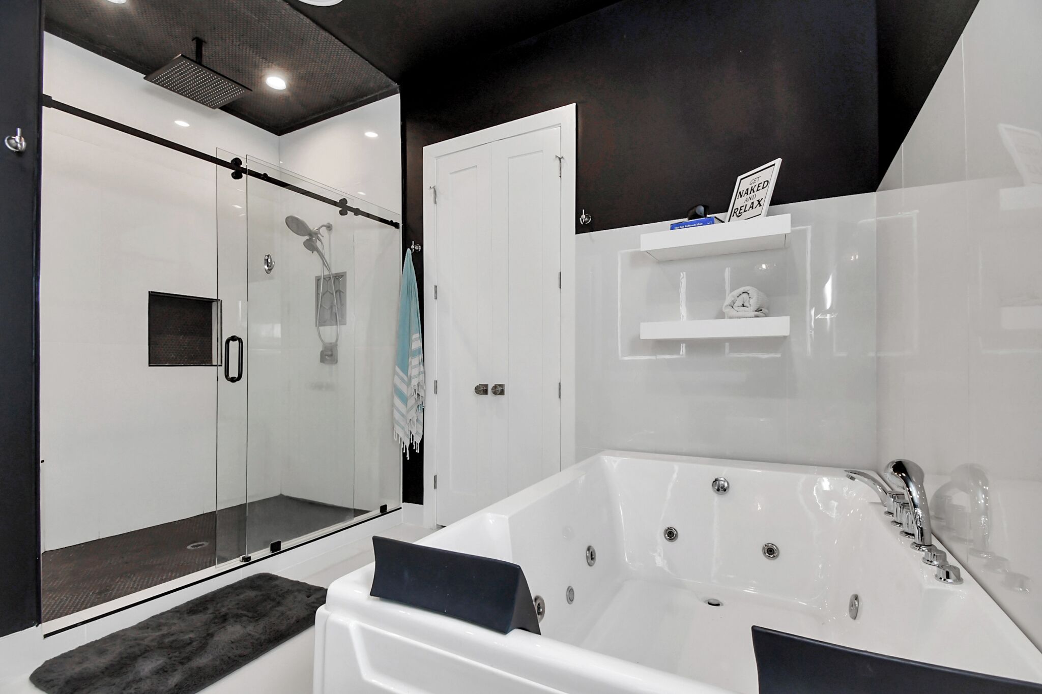 Een moderne badkamer met een glazen douchecabine, een ruime badkuip en een witte wastafel met spiegel.