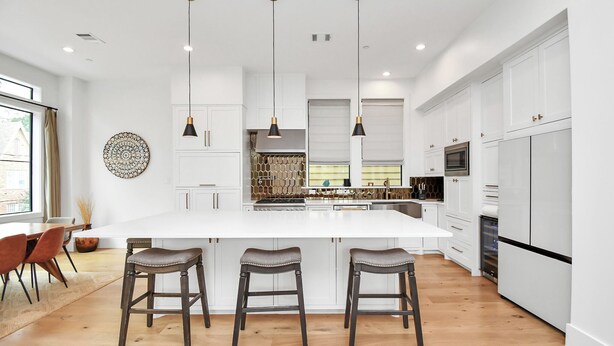 Een moderne keuken met een centraal eiland, hangende verlichting en witte kasten.