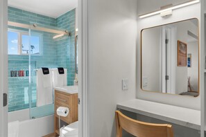 A bathroom with a glass shower enclosure, a wooden chair, a mirror, and a towel rack. - Pacific Tides 7 - Modern Studio In Pacific Beach w/ AC + Parking - Walk to Beach (San Diego)