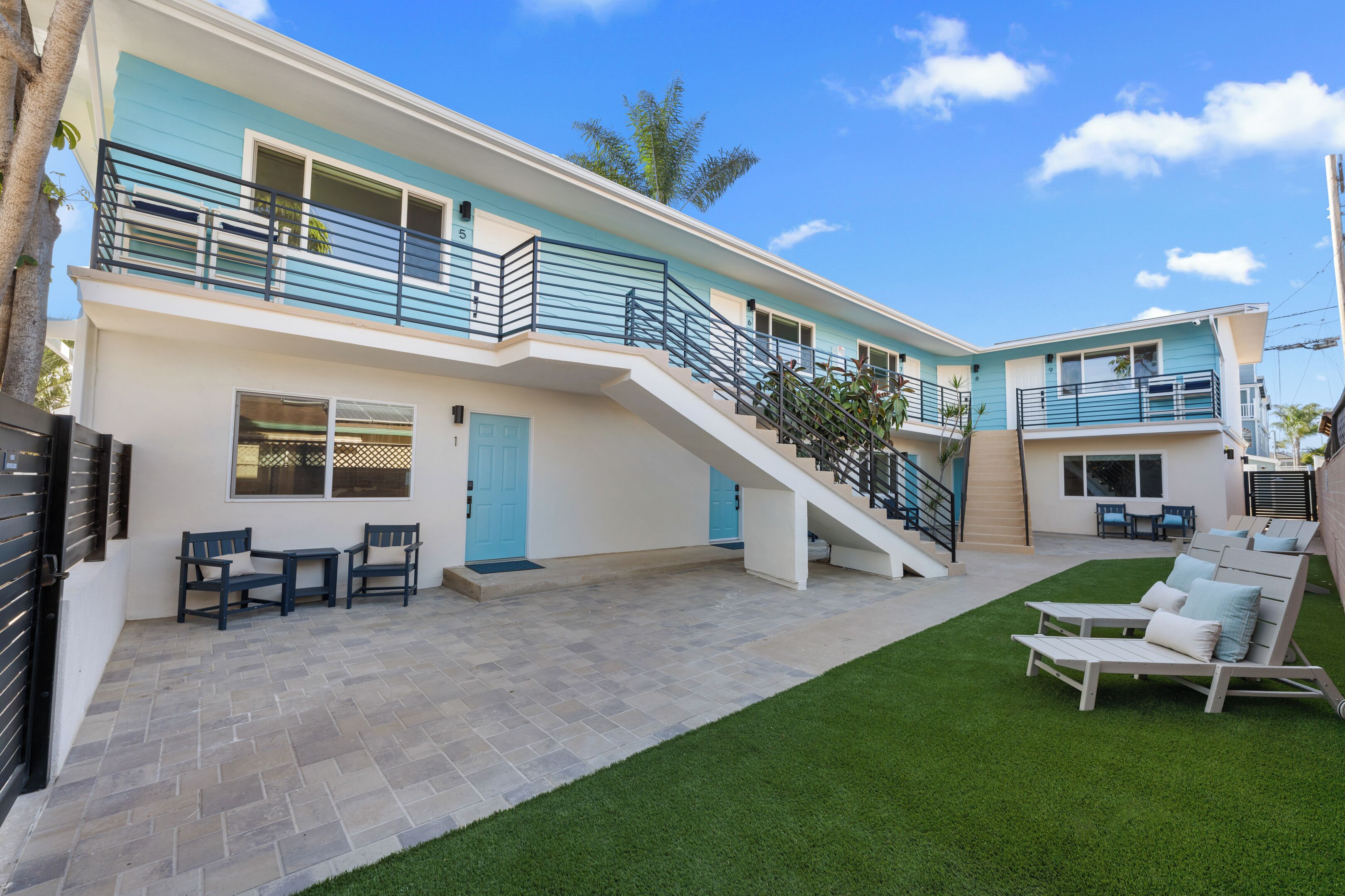 A two-story building with a balcony, outdoor seating, and a staircase.