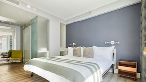 A modern bedroom with a large bed, a bedside table, a chair, and a wardrobe. - The Slate Hotel  (Toronto)