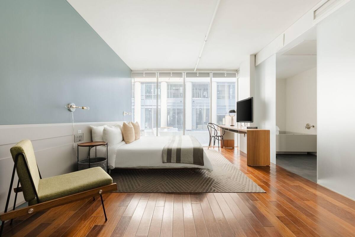 A modern bedroom with a bed, bedside table, and a desk with a chair.