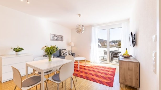 Una sala de estar moderna con comedor, un ventanal y vistas al exterior.