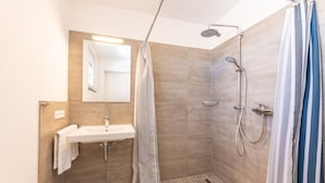 Un baño moderno con ducha, lavabo y espejo.