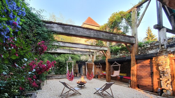 Un espace extérieur rustique aménagé avec des hamacs et un foyer.