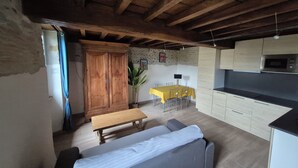 Un salon chaleureux avec un canapé, une table en bois et une cuisine en arrière-plan.