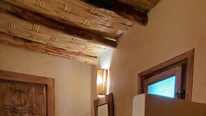 Een rustieke badkamer met een houten deur, een wastafel met een gevlochten mand, een toilet en een spiegel aan de muur.