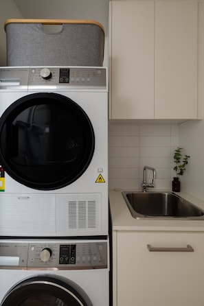A compact washer and dryer unit in a kitchen with a sink and cabinets. - Spacious 2BR Apartment Vibrant Richmond (Richmond)