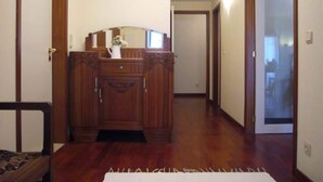 A hallway with wooden flooring, a wooden cabinet, and a white rug. - A Peaceful Riverside Escape Just Minutes from Porto (São Cosme)