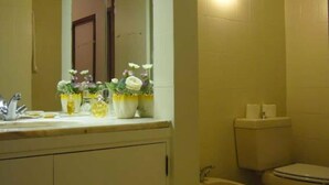 A bathroom with a toilet, bidet, sink, and mirror. There are flower arrangements on the sink counter. - A Peaceful Riverside Escape Just Minutes from Porto (São Cosme)