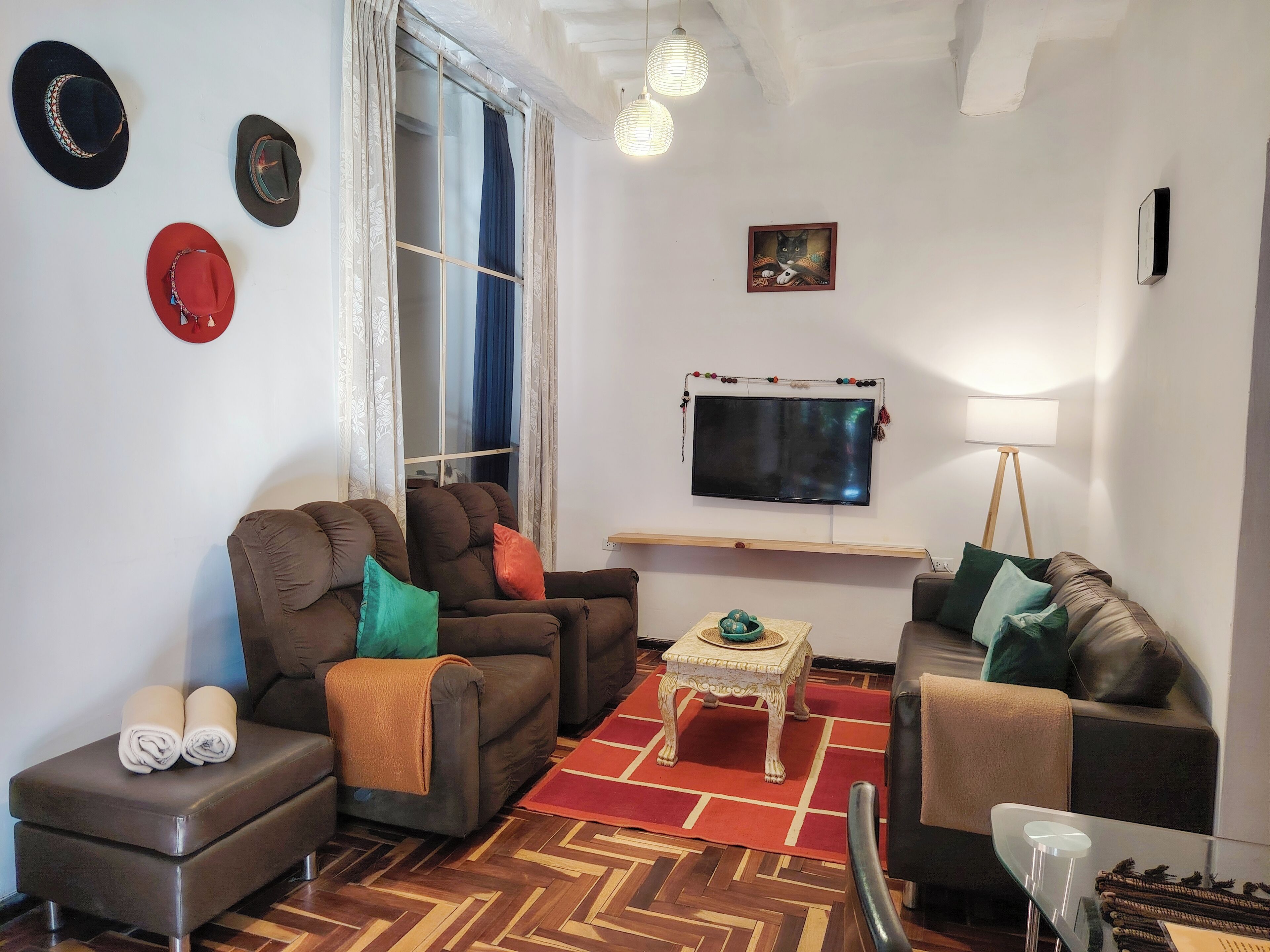 Uma sala de estar com dois sofás, uma mesa de centro, uma televisão e uma janela com cortinas.