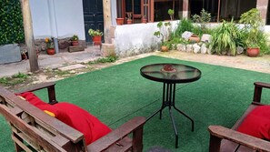 Une terrasse avec un revêtement de gazon synthétique, une table ronde et des chaises en bois.