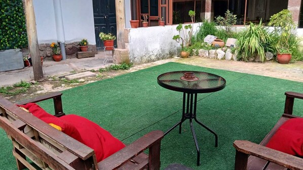 A patio with artificial grass, a round table, and wooden chairs. - KANTIQ House (Cusco)