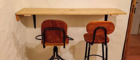 A room with a wooden desk, two chairs, two wall-mounted mirrors, and a map artwork.