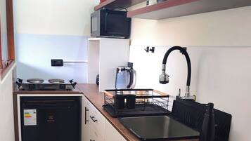 A compact kitchen with a stove, sink, and storage cabinets.