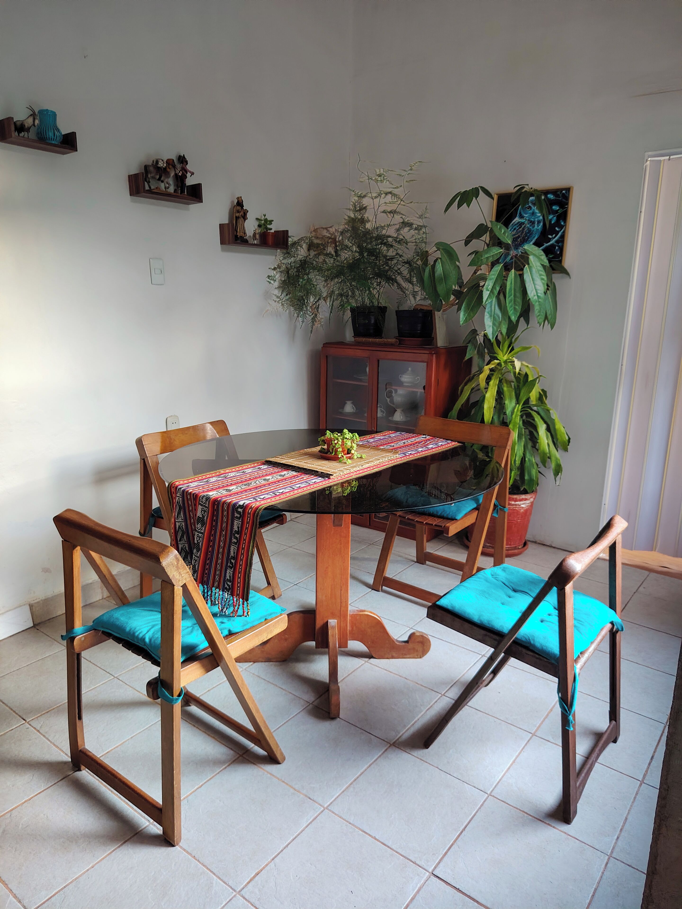 A dining area with a round table, wooden chairs, and a patterned table runner.