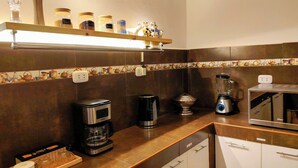 A kitchen with a coffee maker, blender, and a shelf with jars.