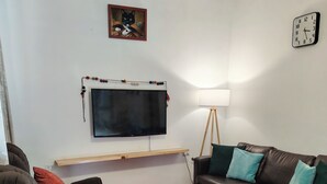 A living room with a sofa, a coffee table, a TV, and a clock on the wall.