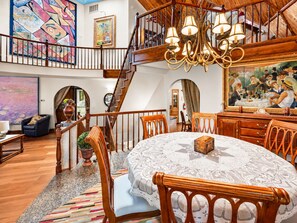 Ein geräumiger Essbereich mit hohen Decken und einer Chandelier, Holzsessel und ein gedeckter Tisch.