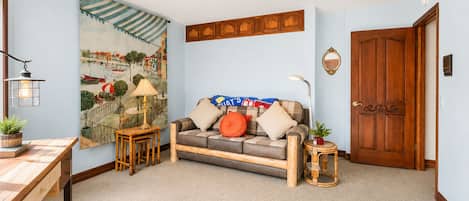 Un salon confortable avec un canapé, une table, une lampe et un tableau accroché au mur.