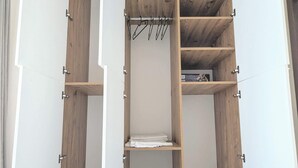Een inloopkast met houten planken en een kledingroede.