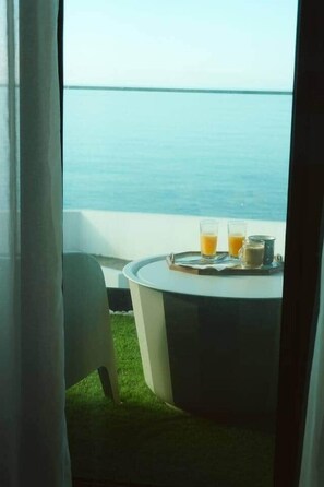 A table with two glasses of orange juice and a cup, set on a balcony with a view of the sea. - Vista at Madeira Home Cliff Residence Stunning Sea Views near airport and beach (Gaula)