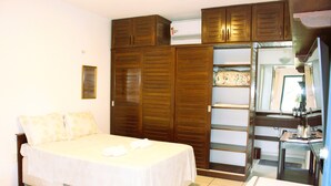 A bedroom with a bed, wardrobe, and a bathroom with a sink and mirror. - Spacious house with garden and 3 suites in Novo Airão. (Novo Airão)