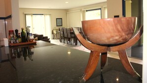 A modern kitchen with a black countertop, wooden chairs, and a dining area with a table and chairs. - Spacious house with garden and 3 suites in Novo Airão. (Novo Airão)